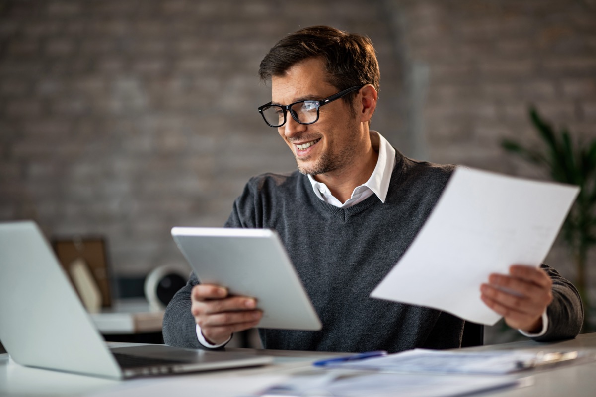 A business professional reviewing documents and marketing materials at a desk